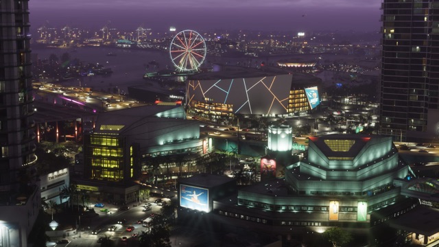 Downtown Vice City at night from above: an arena streaked with neon lines, an arts center and a ballet billboard in the foreground, and a Ferris wheel and port cranes across the bay.
